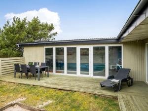 ein Haus mit einer Terrasse mit einem Tisch und Stühlen in der Unterkunft Holiday Home Yorik - 800m from the sea by Interhome in Hvide Sande