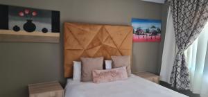 Un dormitorio con una cama blanca con cabecero de madera. en Villa king quest house, en Ga-Rankuwa