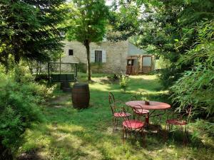 a table and chairs in the yard of a house at Le chant de la rivière in Carla-de-Roquefort