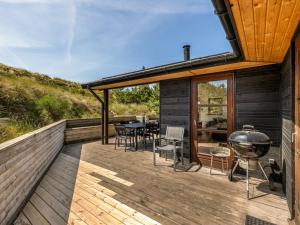 eine Terrasse mit einem Grill, einem Tisch und Stühlen in der Unterkunft Holiday Home Sila - 800m from the sea by Interhome in Hvide Sande