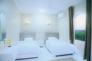 two beds in a white room with a window at Paradise House Holiday in Luxor