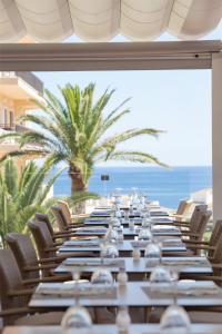 a long table with chairs and the ocean in the background at Hotel Bella Playa & Spa in Cala Ratjada