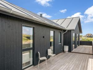 una casa nera con due sedie su una terrazza di Holiday Home Maximiliane - from the sea by Interhome a Ringkøbing