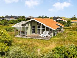 ein grünes Haus mit orangefarbenem Dach auf einem Feld in der Unterkunft Holiday Home Gedda - 700m from the sea by Interhome in Hvide Sande + 25 Fotos