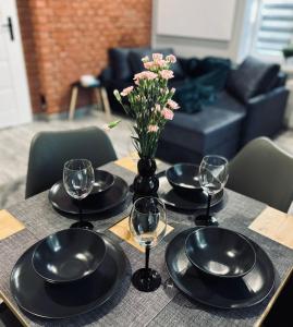 einen Tisch mit Tellern und Gläsern und eine Vase mit Blumen in der Unterkunft Apartament 87 in Jelenia Góra