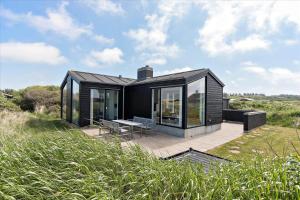 una casa nera seduta su un patio in un campo di LN1598-Hjorring-Kystmarken-46 a Hjørring