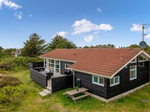 ein schwarzes Haus mit einem Picknicktisch davor in der Unterkunft Holiday Home Andrie - 800m from the sea by Interhome in Hvide Sande