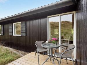 a black house with a table and chairs on a deck at Holiday Home Hélène - 400m from the sea by Interhome in Havrvig