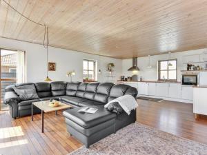 a living room with a black leather couch and a kitchen at Holiday Home Ottmar - from the sea by Interhome in Hvide Sande