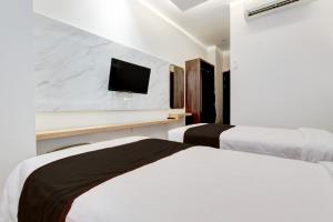 a bedroom with two beds and a tv on a wall at Townhouse OAK Near The Park Mall Semarang Formerly Semarang Boutique Hotel in Semarang