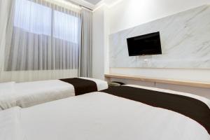 due letti in una stanza d'albergo con una TV a parete di Townhouse OAK Near The Park Mall Semarang Formerly Semarang Boutique Hotel a Semarang Altre 36 foto
