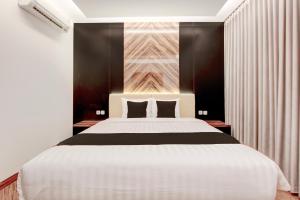 a bedroom with a large white bed with black walls at Townhouse OAK Near The Park Mall Semarang Formerly Semarang Boutique Hotel in Semarang