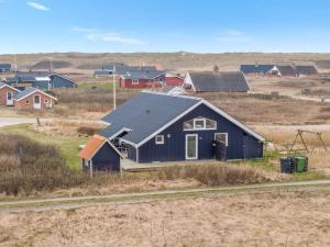 a blue house in a field with houses in the background at Holiday Home Galmand - 300m from the sea by Interhome in Lemvig