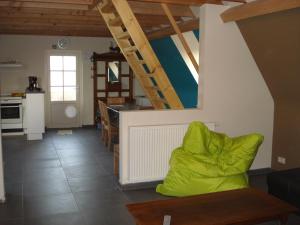 a living room with a green couch and a kitchen at Holiday home Het Zeugekot in Beveren