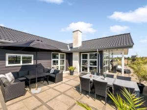 a patio with tables and chairs and an umbrella at Holiday Home Ennie - from the sea by Interhome in Bjerregård