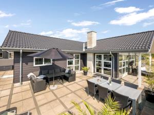 a patio with an umbrella and tables and chairs at Holiday Home Ennie - from the sea by Interhome in Bjerregård