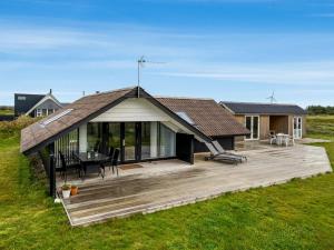 a house with a wooden deck in a field at Holiday Home Olesia - 250m from the sea by Interhome in Harboør