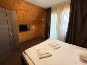 a bedroom with a bed with two towels on it at Vila Casa Familiei Poiana Braşov in Poiana Brasov