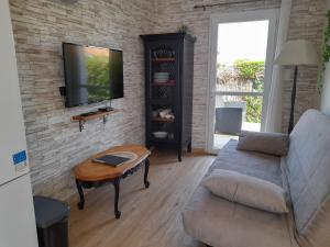 a living room with a couch and a tv on a brick wall at Le rocher in Longeville-sur-Mer