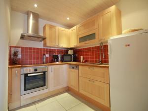eine Küche mit Holzschränken und einem weißen Kühlschrank in der Unterkunft Appartement 3 pièces - 6 pers - Proche pistes et commerces, navette gratuite - FR-1-572-19 in Arâches-la-Frasse