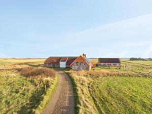 a house in the middle of a field with a dirt road at Holiday Home Answald - 250m from the sea by Interhome in Harboør