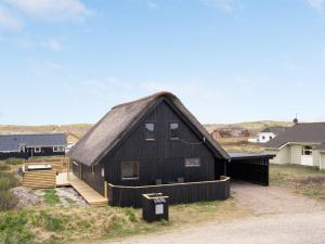 a black barn with a thatched roof at Holiday Home Kristanna - 150m from the sea by Interhome in Harboør