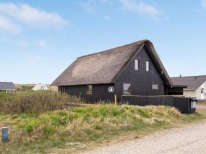 a black barn on the side of a dirt road at Holiday Home Kristanna - 150m from the sea by Interhome in Harboør