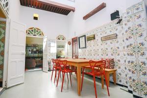 a dining room with a wooden table and red chairs at Riad Gabrielle Maison d'Artiste au coeur de la Medina in Salé