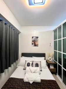 un dormitorio con una cama con sábanas y almohadas blancas en Pasay Mall of Asia Shore1 Residences Tower C2, en Manila