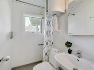 a white bathroom with a toilet and a sink at Holiday Home Majgull - 150m from the sea by Interhome in Torsted