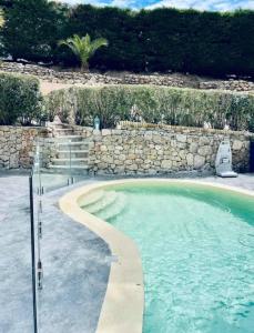 a swimming pool with a stone wall and a pathway at BAS DE VILLA, Mer Piscine et SPA in Roquebrune-sur-Argens