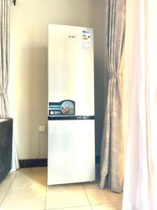 un réfrigérateur blanc dans une pièce avec des rideaux dans l'établissement The Peace Haven, à Kampala