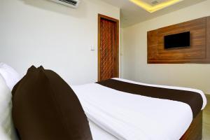 a bedroom with a white bed with a tv on the wall at Hotel O Angel Park in Ahmedabad