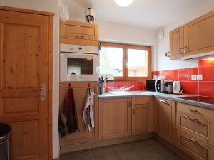 eine Küche mit Holzschränken und einer Spüle in der Unterkunft 3 pièces cosy : Jardin, Wifi, Parking, 700m des pistes, 50m des commerces - FR-1-572-44 in Arâches-la-Frasse + 5 Fotos