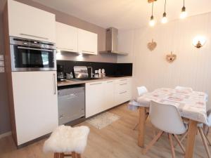 cocina con mesa y cocina con armarios blancos en Charme au centre d'Arâches : 2 pièces + coin montagne, 4/5 pers, proche pistes et commerces - FR-1-572-154, en Les Carroz d'Araches