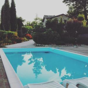 a blue swimming pool with two chairs and a house at Casale il Cerqueto in San Severino Marche +45 photos