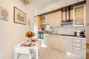 a kitchen with white cabinets and a table with flowers at La Casa di Ale 1 - Castelli Romani in Marino