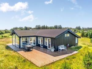una pequeña casa con terraza en un campo en Holiday Home Hildegardt - 1km from the sea by Interhome, en Løkken