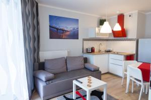 ein Wohnzimmer mit einem Sofa und einer kleinen Küche in der Unterkunft Apartament Międzyzdroje Horyzont Blue in Misdroy