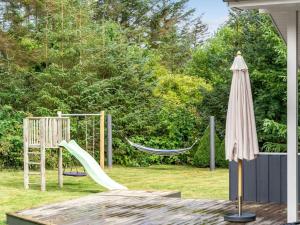 a playground with a hammock and an umbrella at Holiday Home Dimo - 700m from the sea by Interhome in Løkken +20 photos
