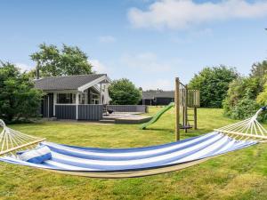 a hammock in a yard with a house at Holiday Home Dimo - 700m from the sea by Interhome in Løkken