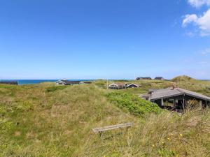 a bench sitting on a grassy hill next to a house at Holiday Home Tulir - 300m from the sea by Interhome in Løkken