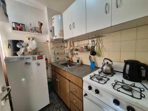 Il comprend une cuisine équipée d'une cuisinière et d'un réfrigérateur blanc. dans l'établissement Departamento monoambiente Plaza Mitre, à Mar del Plata