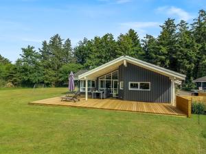 a small house with a wooden deck in a yard at Holiday Home Aniki - 1-4km from the sea by Interhome in Løkken