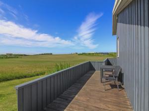 a deck with a table and a chair on the side of a building at Holiday Home Marne - 500m from the sea by Interhome in Løkken