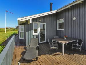 a house with a table and chairs on a deck at Holiday Home Marne - 500m from the sea by Interhome in Løkken