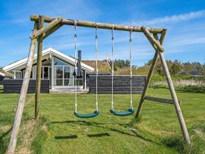 a swing in a yard with a house at Holiday Home Eddi - 550m from the sea by Interhome in Løkken