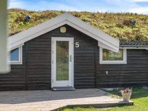 a black house with a grass roof with a door at Holiday Home Eddi - 550m from the sea by Interhome in Løkken