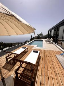 a deck with benches and an umbrella next to a pool at Casa Arriettas in Tijarafe