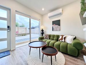 un soggiorno con un divano verde e un tavolo di Family Oasis 3BR vs Backyard Near Beach in Torbay ad Auckland